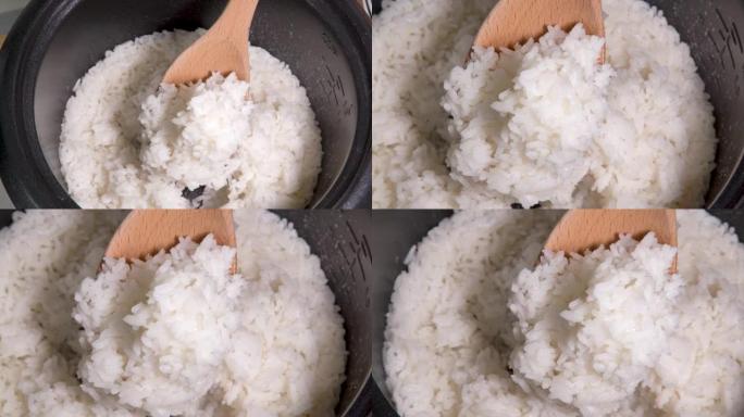 用饭勺从锅里舀米饭，用木勺在锅里煮米饭