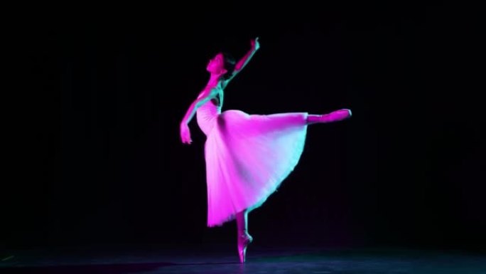 独奏。美丽而优美的芭蕾舞演员在霓虹灯下在黑暗的剧院舞台上跳舞。艺术，幻想，灵活性，灵感概念。