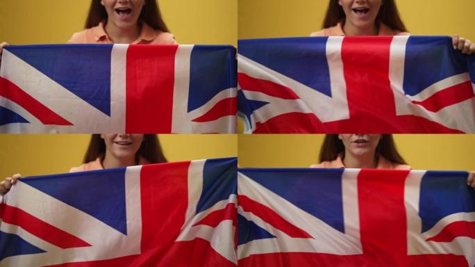 兴奋的无法辨认的妇女摇晃英国国旗在慢动作的黄色背景。快乐骄傲的女士吹牛英国国旗微笑欣喜。