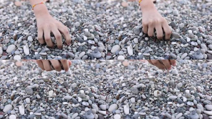 一个孩子的手捡起并倒出海卵石