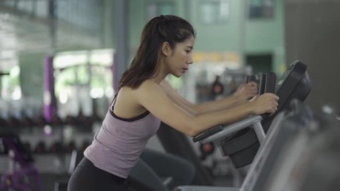 两个穿着黑色服装和紧身裤的亚洲女孩在健身房锻炼。做运动和健身训练健康的生活方式。