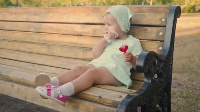 一个2岁的女孩吃冰淇淋，自己用湿纸巾擦拭脸