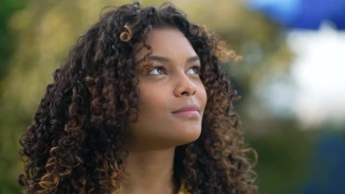 一位黑人年轻女子仰望天空，充满希望和信念。精神20岁成人非洲裔美国女孩特写脸感激