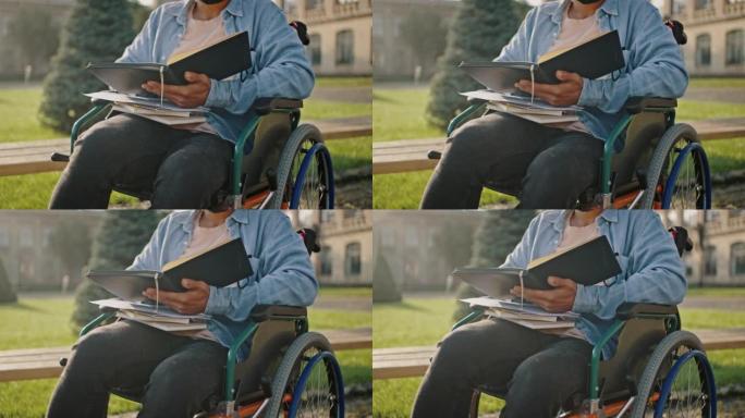 残疾男学生坐在轮椅上阅读教科书