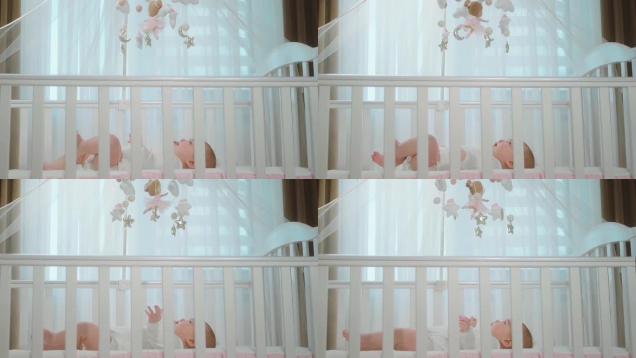 迷人可爱的女婴，躺在婴儿床上，专注于婴儿床玩具。在阿里·阿列克谢迷你上拍摄。