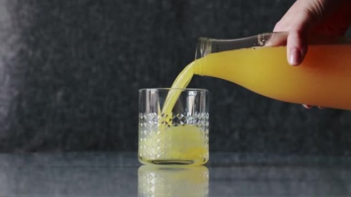 橙汁从不在框架中的瓶子倒入玻璃杯中。