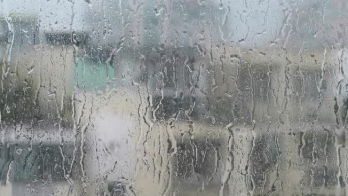 潮湿的窗户玻璃表面上的水滴。大雨随机落在窗户上滑动。4k镜头实时。