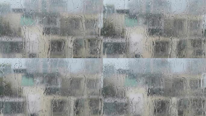 潮湿的窗户玻璃表面上的水滴。大雨随机落在窗户上滑动。4k镜头实时。