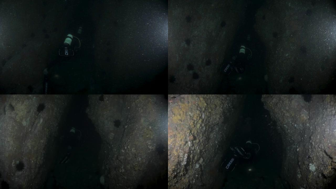 水肺潜水员通过水下深处的狭窄岩石通道跟随一队洞穴潜水员
