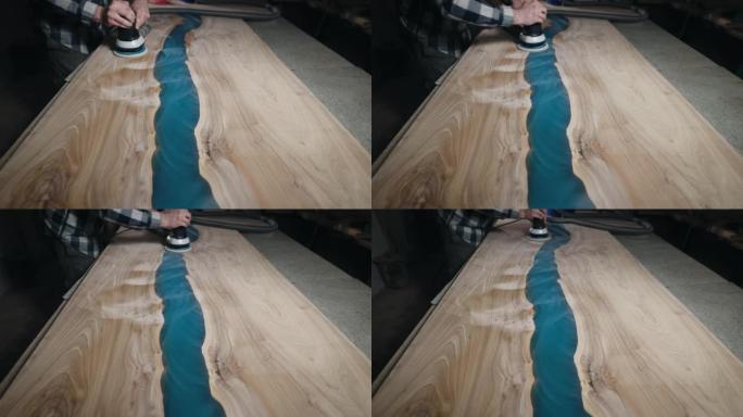木匠用研磨机加工木制桌面的表面。用环氧树脂填充的板坯。