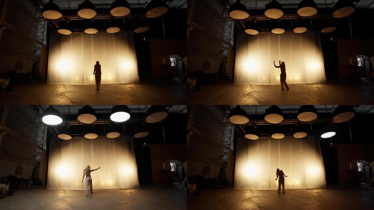 专业舞者在柔和温暖的灯光下在工作室表演的剪影