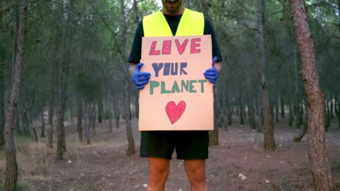生态志愿者在森林里举着“爱地球”的牌子