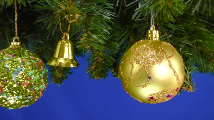 装饰有圣诞装饰品的圣诞树树枝在蓝色背景上旋转
