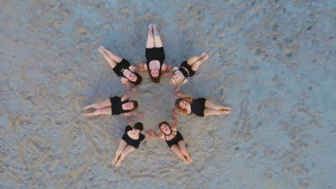 海洋海滩瑜伽，一群混合年龄的妇女坐在圈子里练习和日落冥想