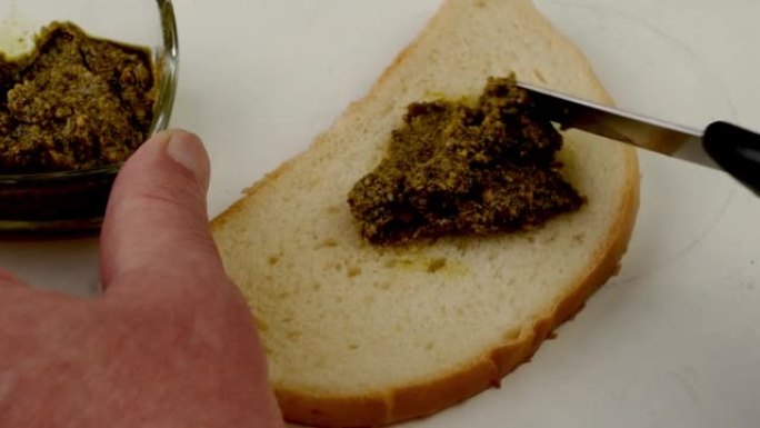 用刀涂在面包上的绿色香蒜酱，用于准备三明治。