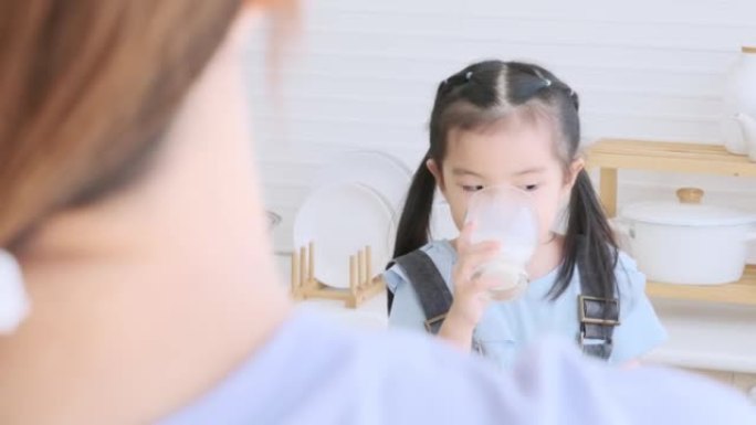 Cute little child girl raise a glass of milk to dr