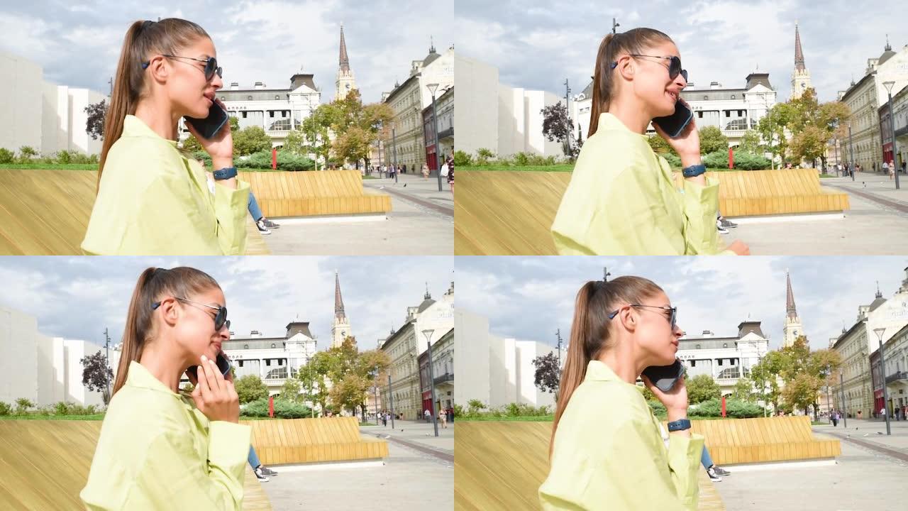 时髦的黑发女人拿着智能手机，在电话里聊天。穿着漂亮的衣服，墨镜走在街上。时尚春夏户外