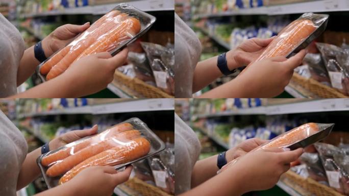 一个女人在超市里拿着包装好的新鲜胡萝卜的特写镜头。