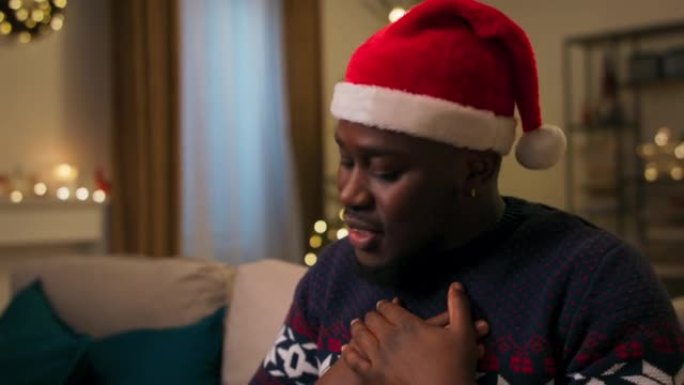 打开圣诞礼物包装的非洲裔男子的手的特写。他解开蓝丝带，打开盒子。令人惊喜的是，这家伙掏出温暖的围巾并