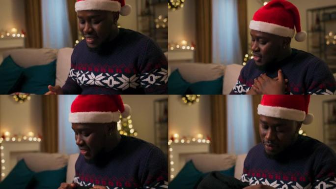 打开圣诞礼物包装的非洲裔男子的手的特写。他解开蓝丝带，打开盒子。令人惊喜的是，这家伙掏出温暖的围巾并