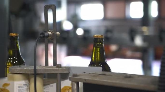 在工业生产输送机上将标签粘贴到酒精瓶上的机器
