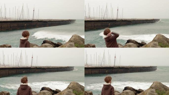 孩子把一块石头扔进波涛汹涌的大海