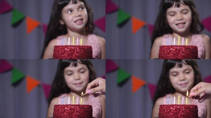 一个六岁女孩坐在蜡烛生日蛋糕旁边的特写镜头。妈妈的手点燃蜡烛。慢动作4k 50 fps