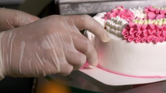 厨师用粉红色的花朵装饰白色蛋糕。