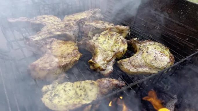 煮熟的多汁牛排肉牛肉用迷迭香刷在燃烧的烤架上，周围有其他肉。慢动作