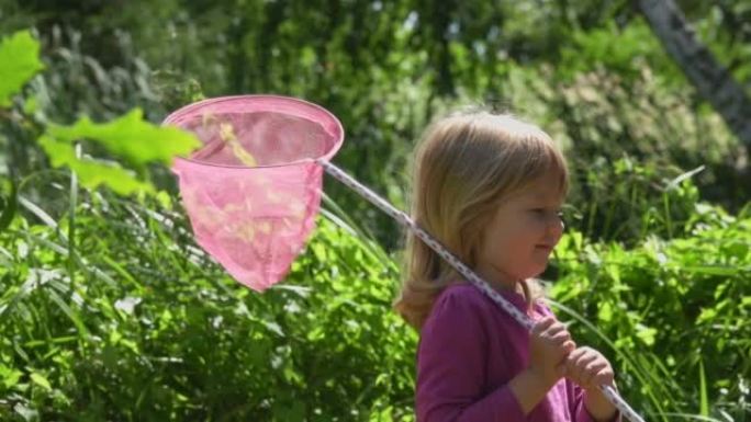 可爱的小女孩，用粉红色的勺子网狩猎虫子和蝴蝶