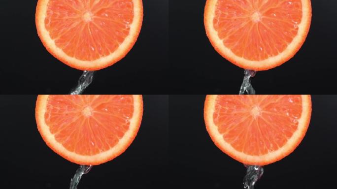 水从黑色背景上的橙色柚子上落下。葡萄柚切片和水飞溅，果汁从多汁的水果中掉落。制作水果鸡尾酒，喝冷柠檬