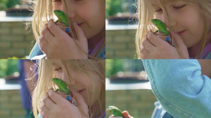 一个小女孩抱着一只绿色的小蜥蜴在亲吻。一个不寻常的宠物。