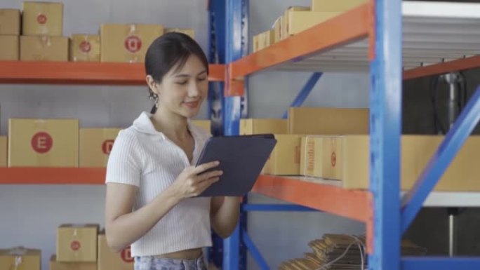 亚洲妇女在仓库用剪贴板检查货架上的商品和材料。中小企业物流及包裹出口业务理念4k。