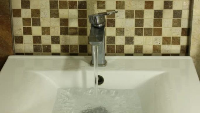 水从水龙头流向洗手盆，流向边缘，概念，用水成本，家庭和居民的价格上涨