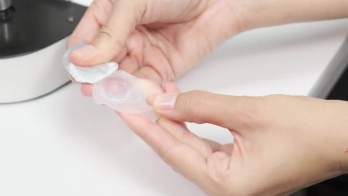 女性验光师的特写镜头打开一个装有隐形眼镜的容器。眼科诊所的眼科检查。验光师在现代诊所的检查中