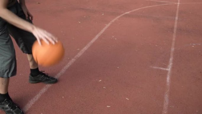 业余篮球运动员练习控球和得分技巧，运球并在公园的街头球场上投篮