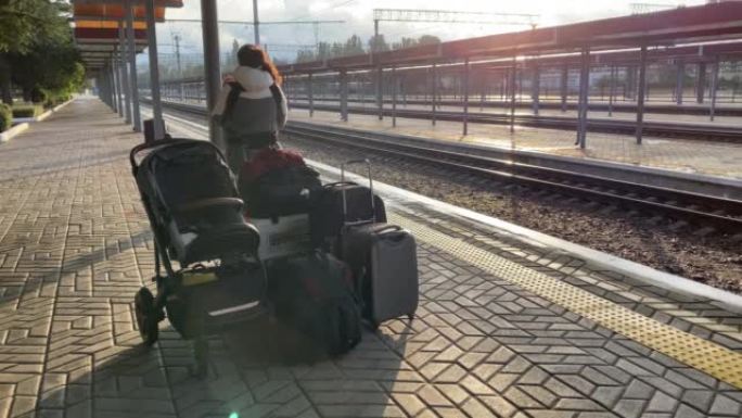 带着小孩乘火车旅行的家庭，带着婴儿和行李的妇女在辛菲罗波尔火车站站台上等待火车的到来。