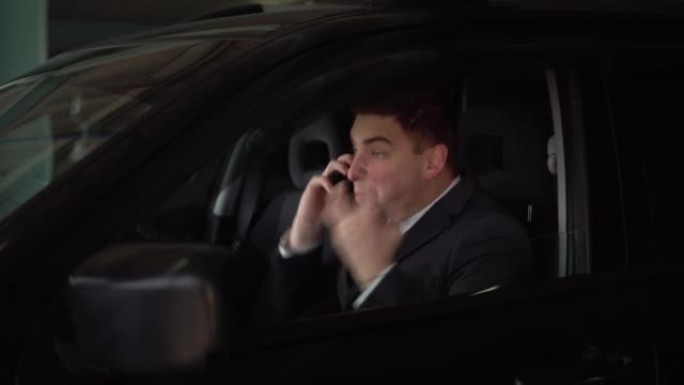 这位年轻的老板坐在停车场的车里，一边在电话里发誓，一边喊叫。愤怒的商人在电话里讲话。4k