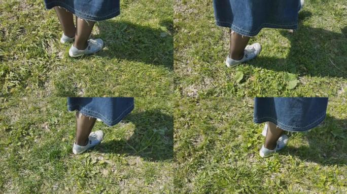 穿着运动鞋和黑色连裤袜的女人的脚去公园里的草地