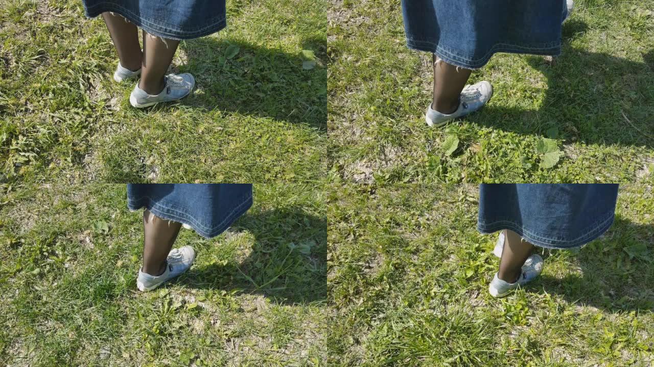 穿着运动鞋和黑色连裤袜的女人的脚去公园里的草地