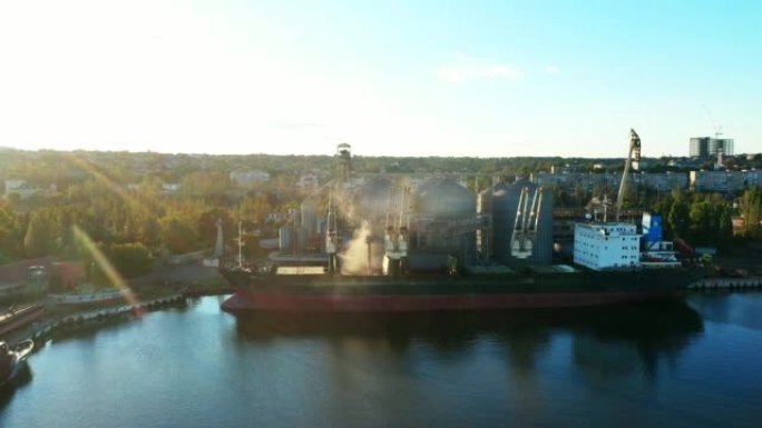 在海港的海粮升降机上，将小麦装载到散装船货舱上。在海港码头通过干线从筒仓到散货船的小麦运输。农产品运