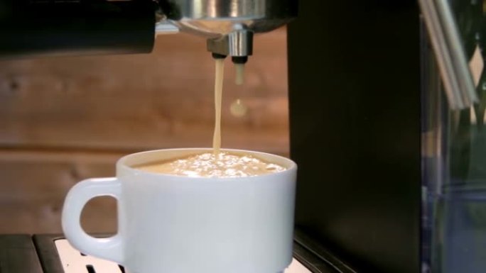 最后一滴浓缩咖啡从咖啡机掉进白色杯子里