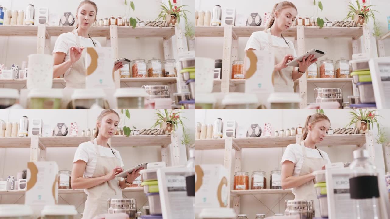 一名女员工在咖啡馆用数字平板电脑拍摄厨房食物。女企业主在后面检查餐馆库存。一名工作并计算烘焙用品的工