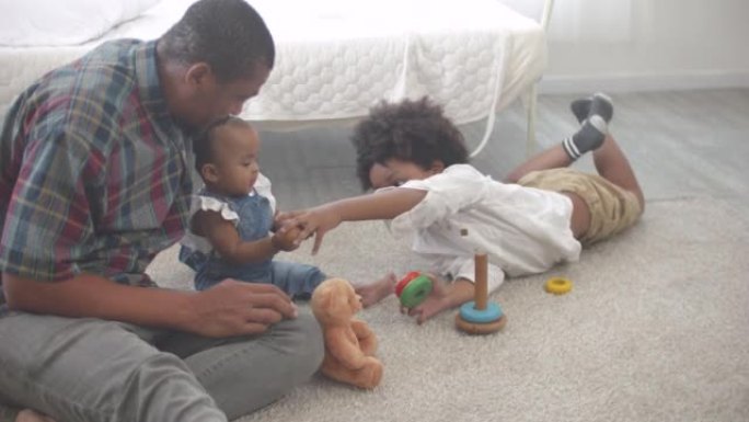 快乐的非洲裔美国爸爸和两个可爱的小孩儿子和女儿在卧室里玩耍和玩耍