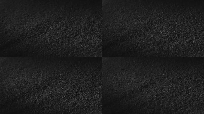 碳粉或黑色炭粉。深色纹理背景。火山尘埃在表面移动，特写