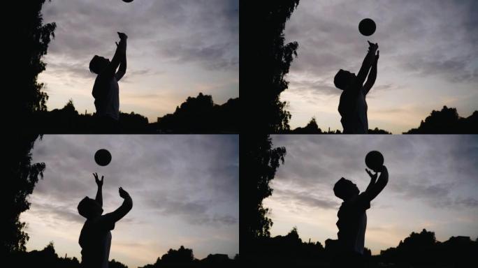 一个人在日落时对着天空打沙滩排球。慢动作中的酷轮廓