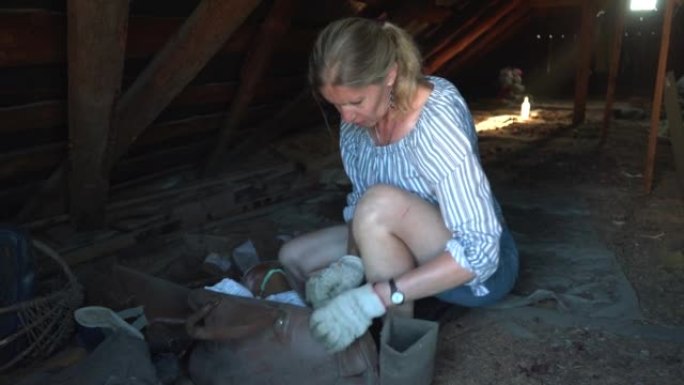 一个女人正在旧阁楼里检查旧东西。
