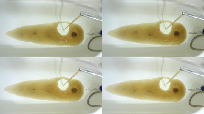 浴缸里从水龙头流出的生锈的水。浴室里有危险的自来水流动。可怕的生锈的水。不适合饮用水管道。下水道排水