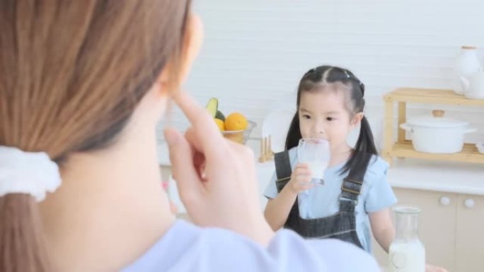 Cute daughter drinking milk with mother for take c