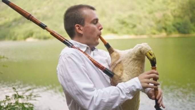 风笛演奏者在山湖上表演民歌的侧视图